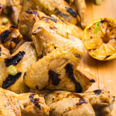 angled shot of yakitori chicken on wooden board with lemon