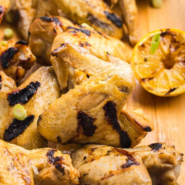 angled shot of yakitori chicken on wooden board with lemon