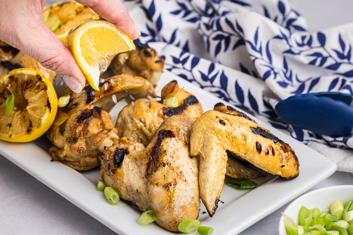 hand squeezing lemon over chicken wings