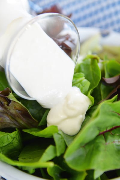 blue cheese dressing pouring over greens