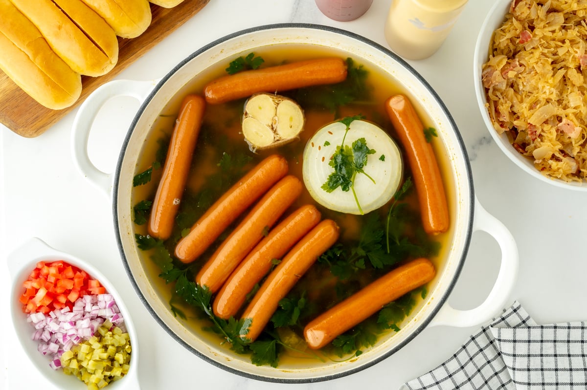 overhead shot of hot dogs in pot of water with seasonings