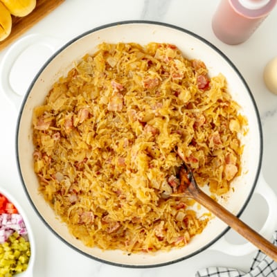overhead shot of beer and bacon sauerkraut in pan with wooden spoon