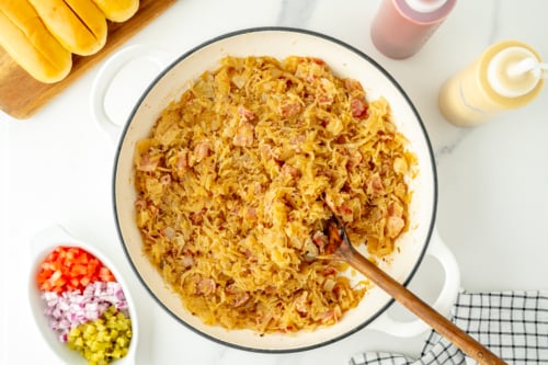 overhead shot of beer and bacon sauerkraut in pan with wooden spoon