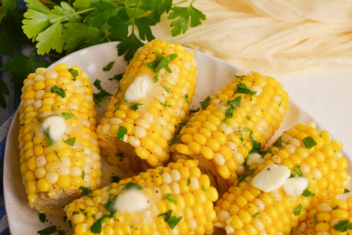 angled shot of platter of corn cobs topped with butter