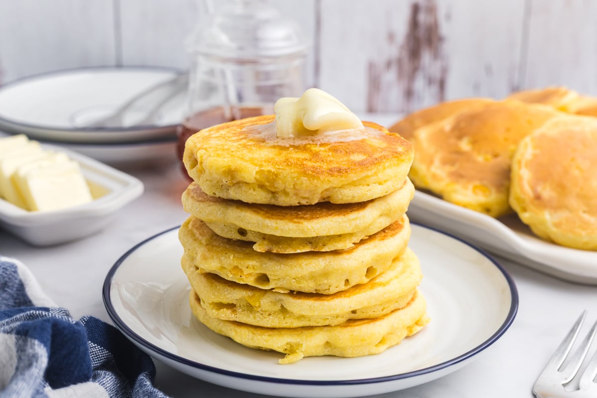 straight on shot of stack of corn cakes on plate topped with butter