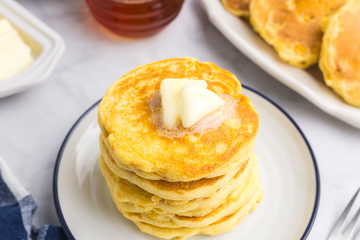 angled shot of butter on stack of griddle corn cakes