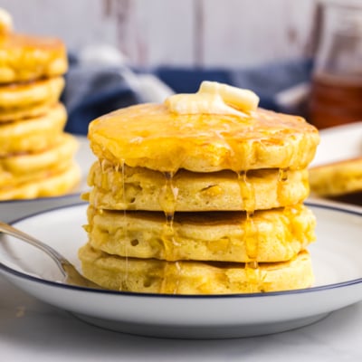 straight on shot of stack of griddle cakes topped with honey