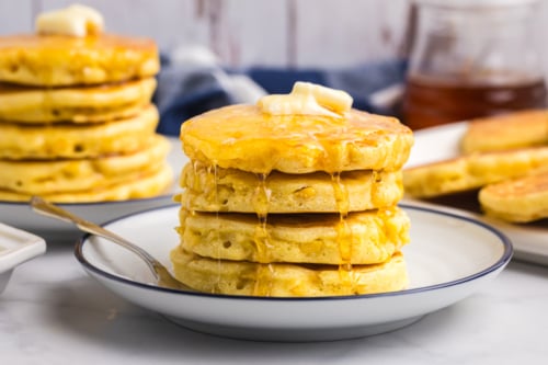 straight on shot of stack of griddle cakes topped with honey