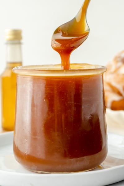 spoon dipping into jar of bourbon caramel sauce