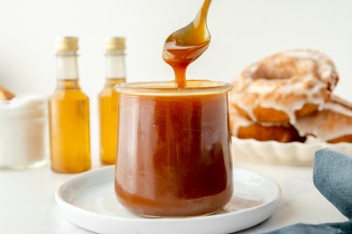 spoon dipping into jar of bourbon caramel sauce