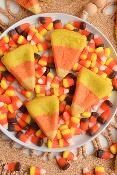 overhead shot of four candy corn cookies on plate of candy corn
