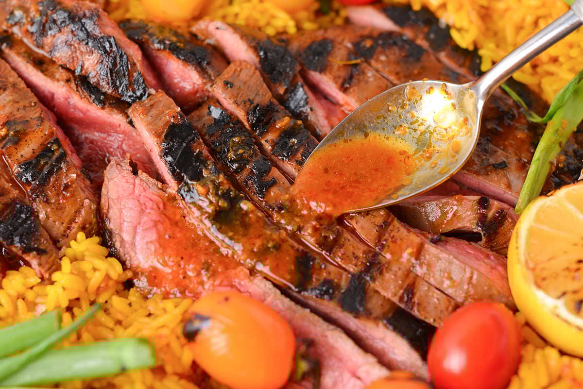 close up of spoon adding sauce to carne asada
