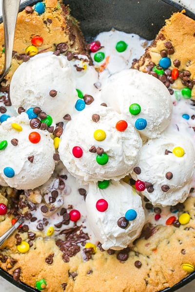 overhead shot of slice taken out of chocolate chip skillet cookie with ice cream