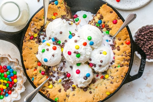 overhead shot of slice taken out of chocolate chip skillet cookie with ice cream
