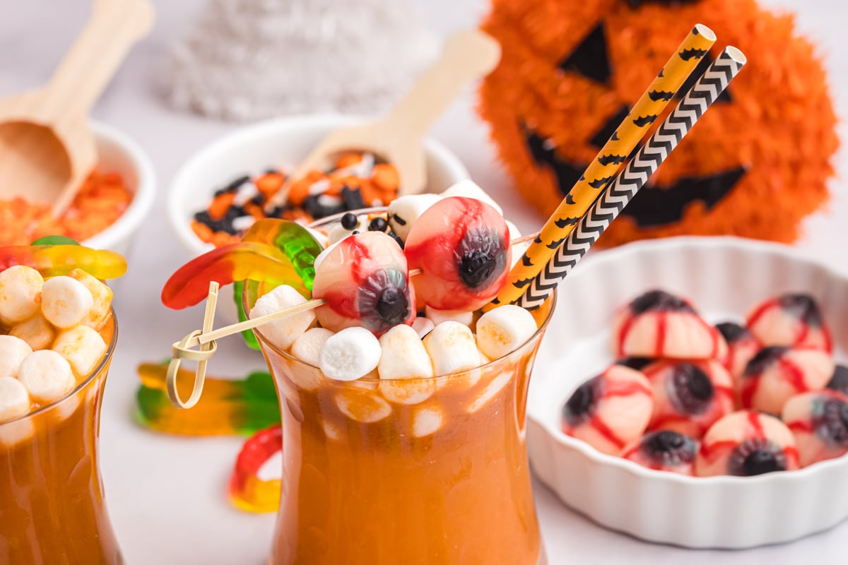 angled shot of glass of orange punch topped with halloween candy