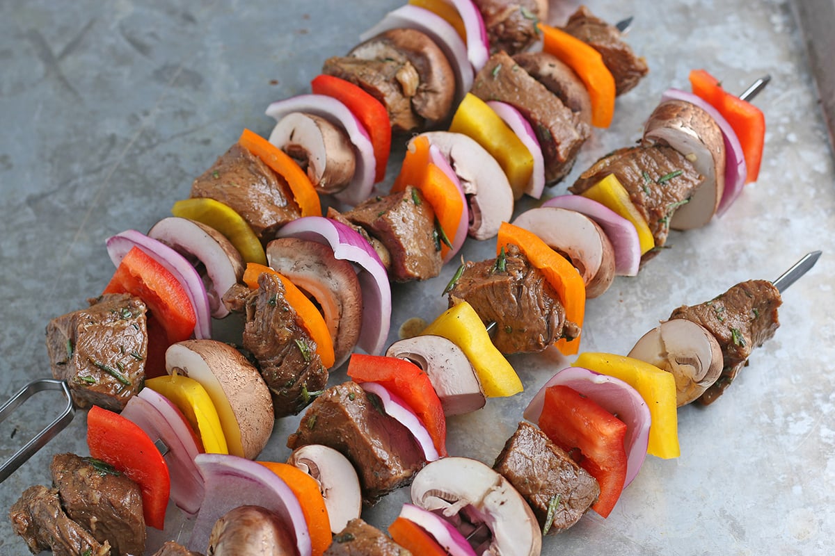 raw steak kabobs on a baking sheet