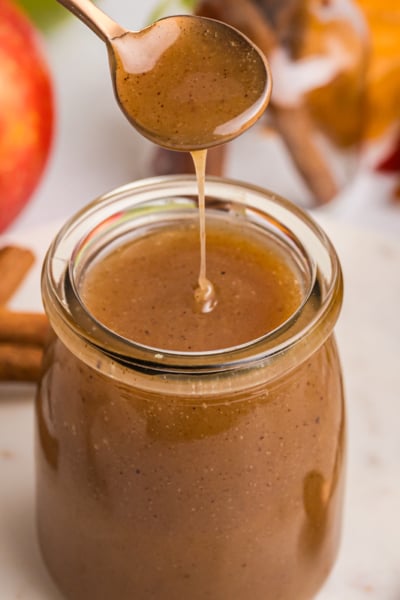 spoon dipping into jar of apple cider caramel sauce