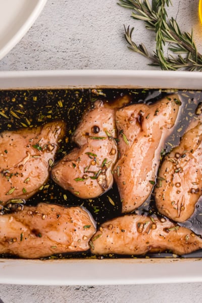 overhead shot of dish of raw chicken on balsamic chicken marinade