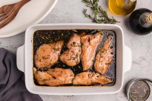 overhead shot of dish of raw chicken on balsamic chicken marinade