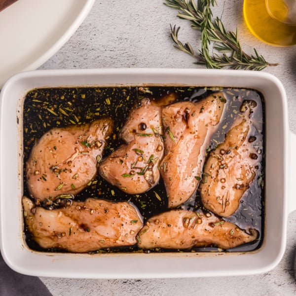 overhead shot of dish of raw chicken on balsamic chicken marinade
