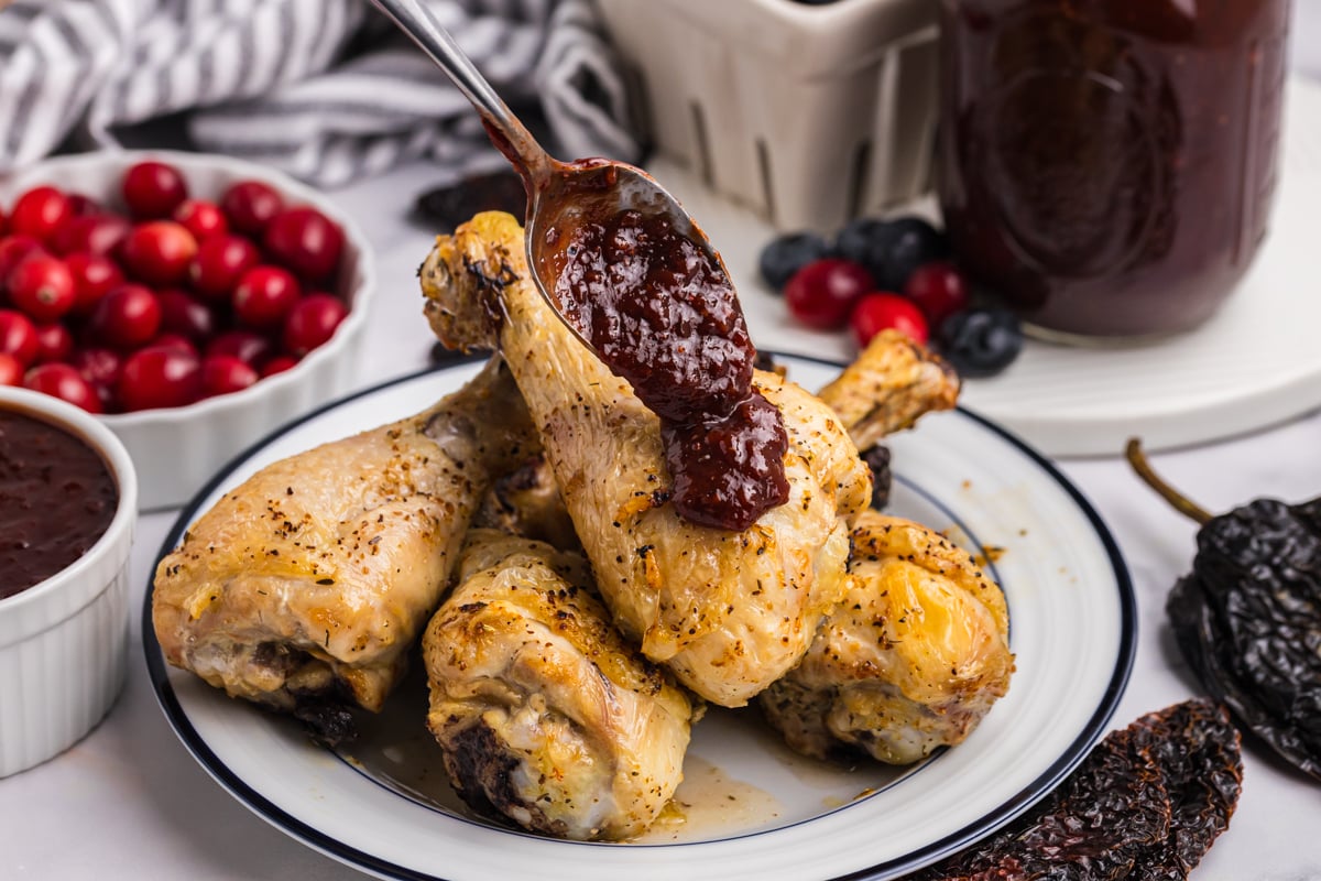 spoon adding bbq sauce to chicken legs
