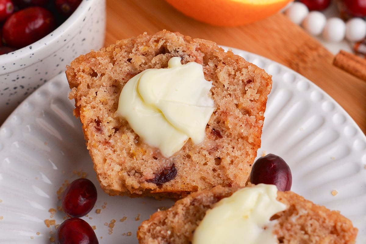 close up of half of a leftover cranberry sauce muffin topped with butter