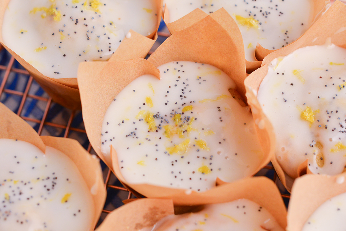 close up angled shot of bakery-style lemon muffins topped with glaze