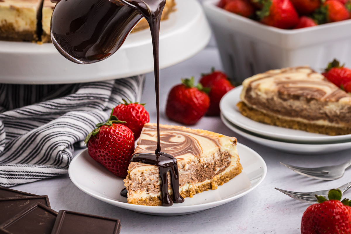 chocolate sauce pouring over slice of marble cheesecake