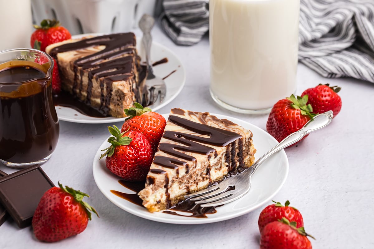 slice of marble new york cheesecake on plate drizzled with chocolate