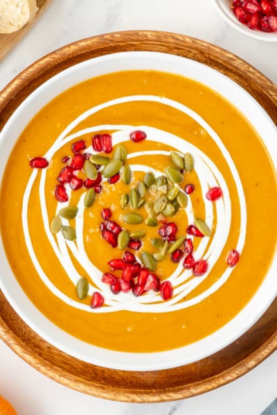 overhead shot of bowl of pumpkin soup topped with pomegranates and pepitas