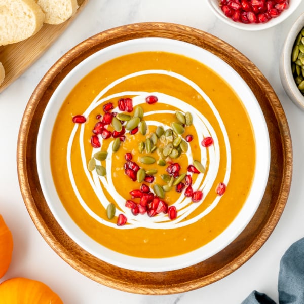 overhead shot of bowl of pumpkin soup topped with pomegranates and pepitas