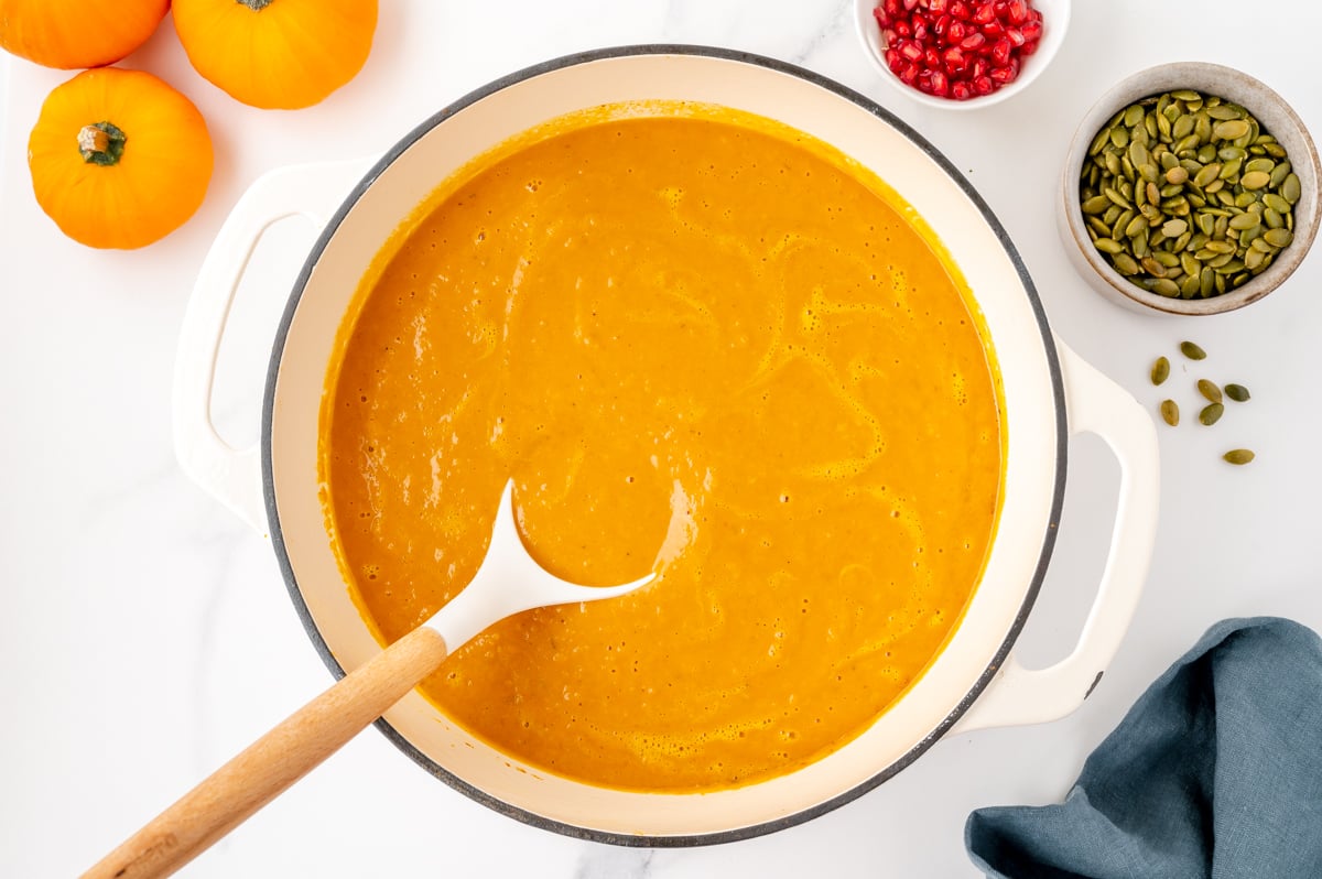 overhead shot of ladle in pot of creamy pumpkin soup