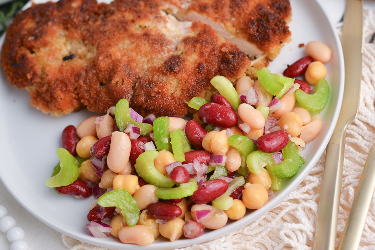 three bean salad on plate with pork chop