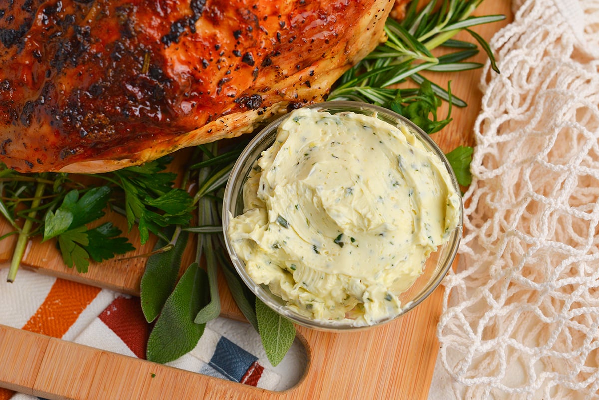 bowl of seasoned butter on board with cooked turkey