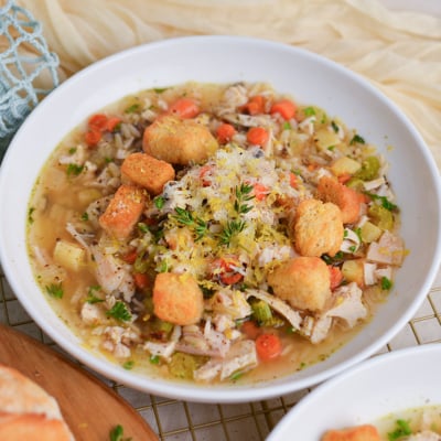 Overhead shot of chicken and wild rice soup topped with fresh parsley, lemon zest, and shaved Parmesan.