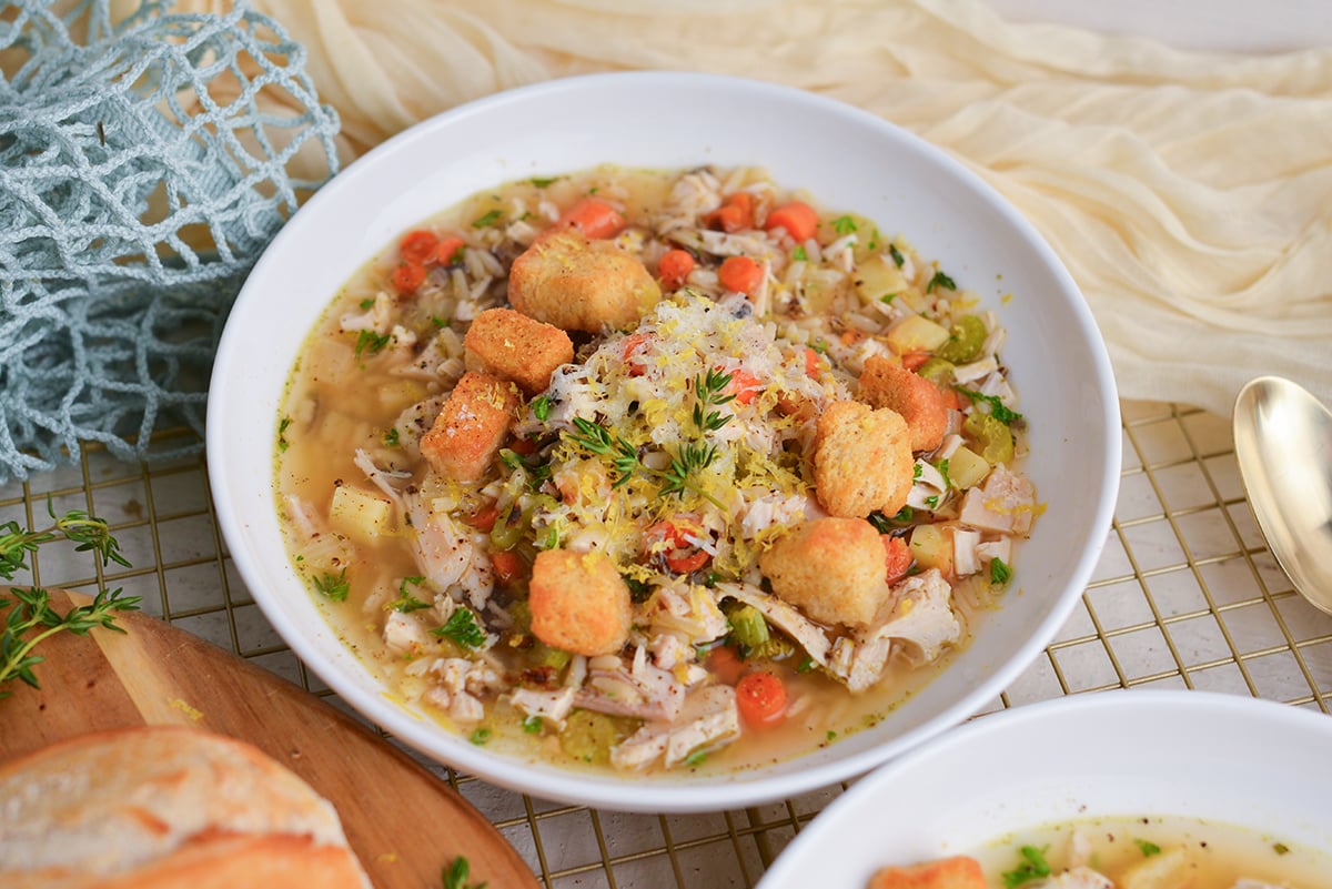 Overhead shot of chicken and wild rice soup topped with fresh parsley, lemon zest, and shaved Parmesan.