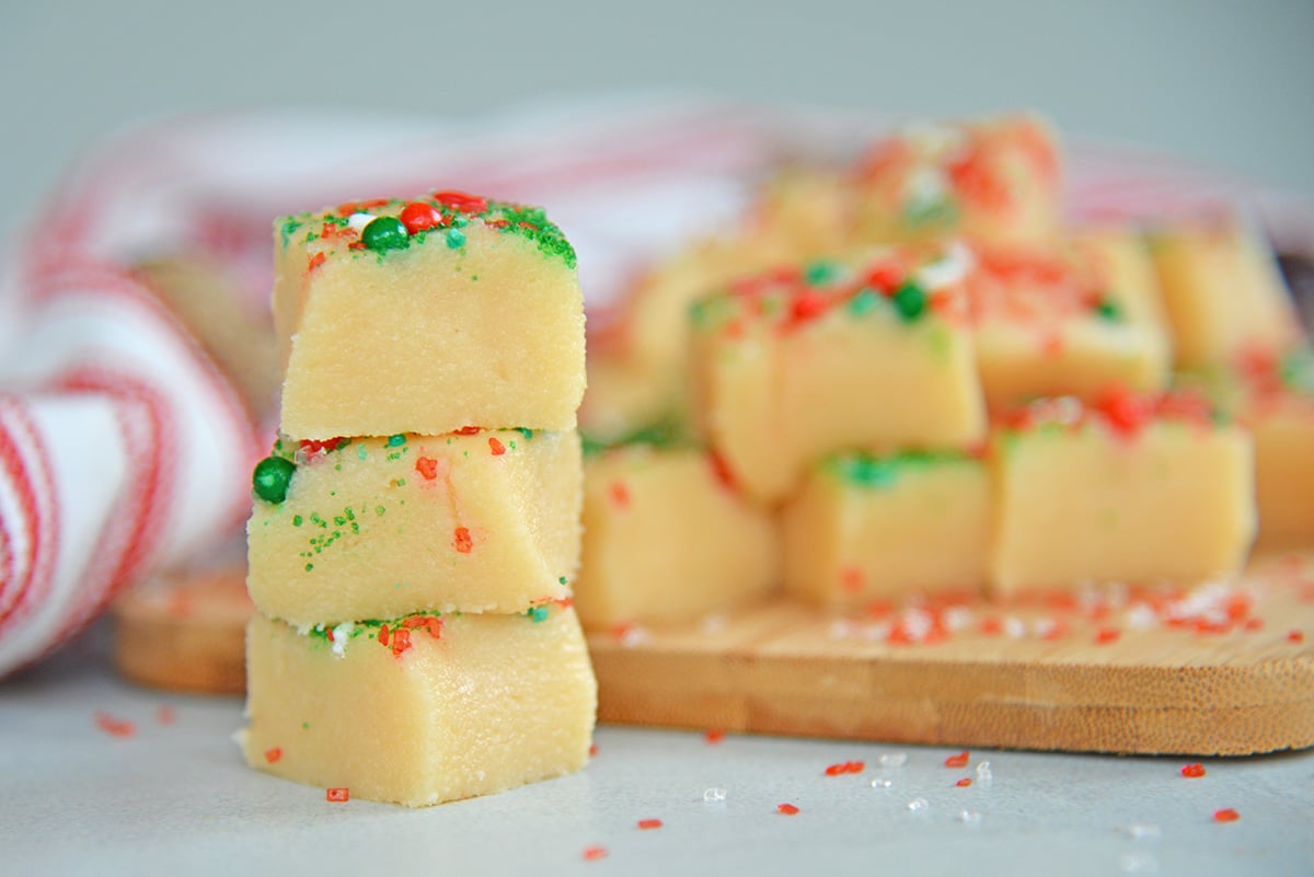 Stack of almond fudge next to a stack on a cutting board