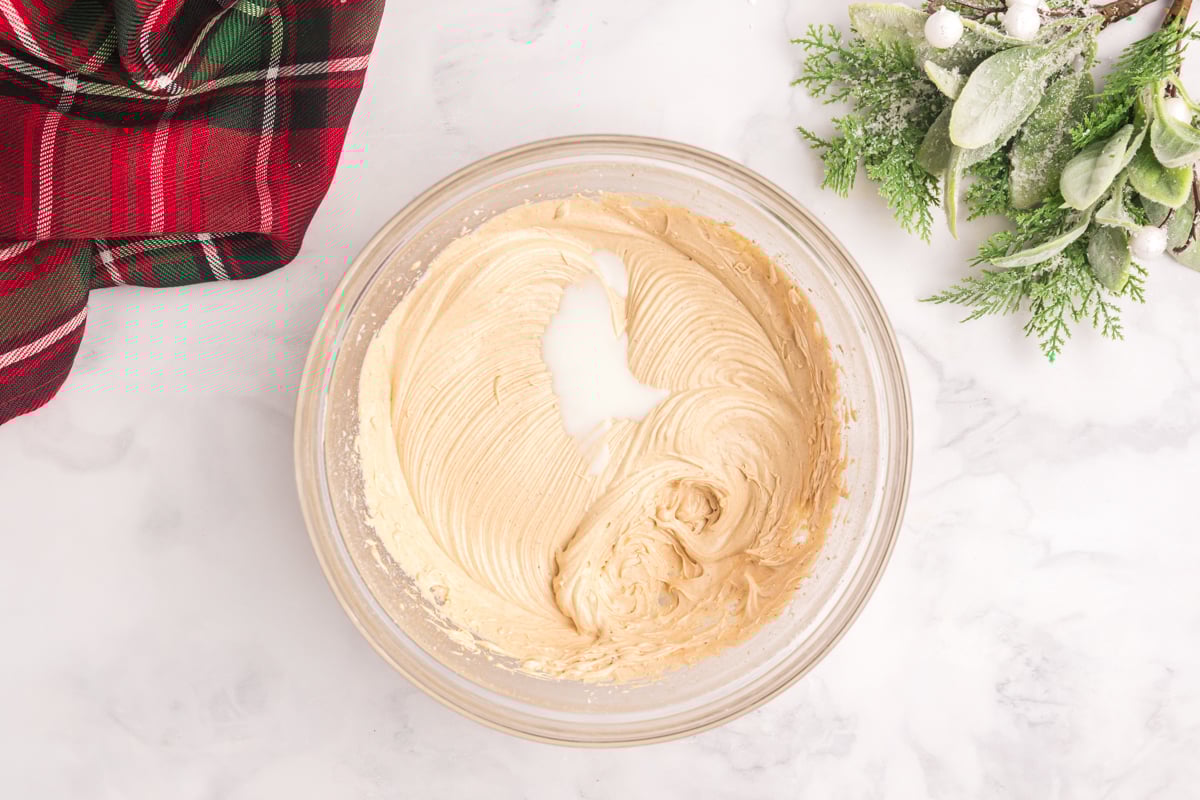 overhead shot of milk added to bowl of frosting