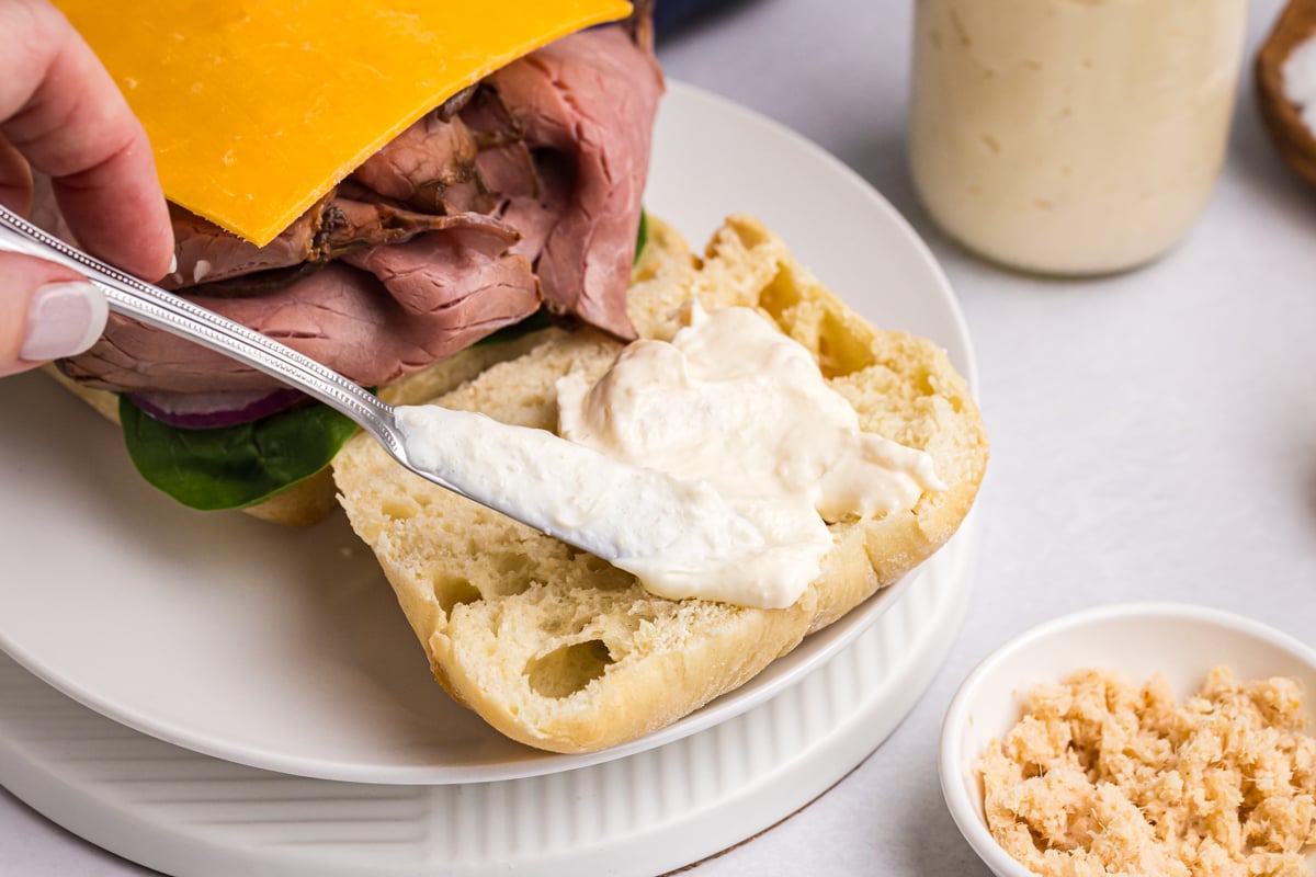 knife slathering aioli onto sandwich bread