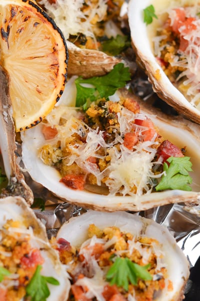 angled shot of cooked oysters on tray with lemon wedges