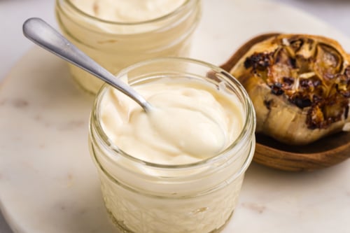 close up of spoon in jar of roasted garlic aioli