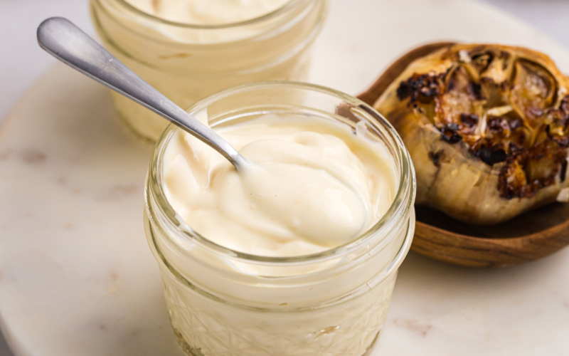 close up of spoon in jar of roasted garlic aioli