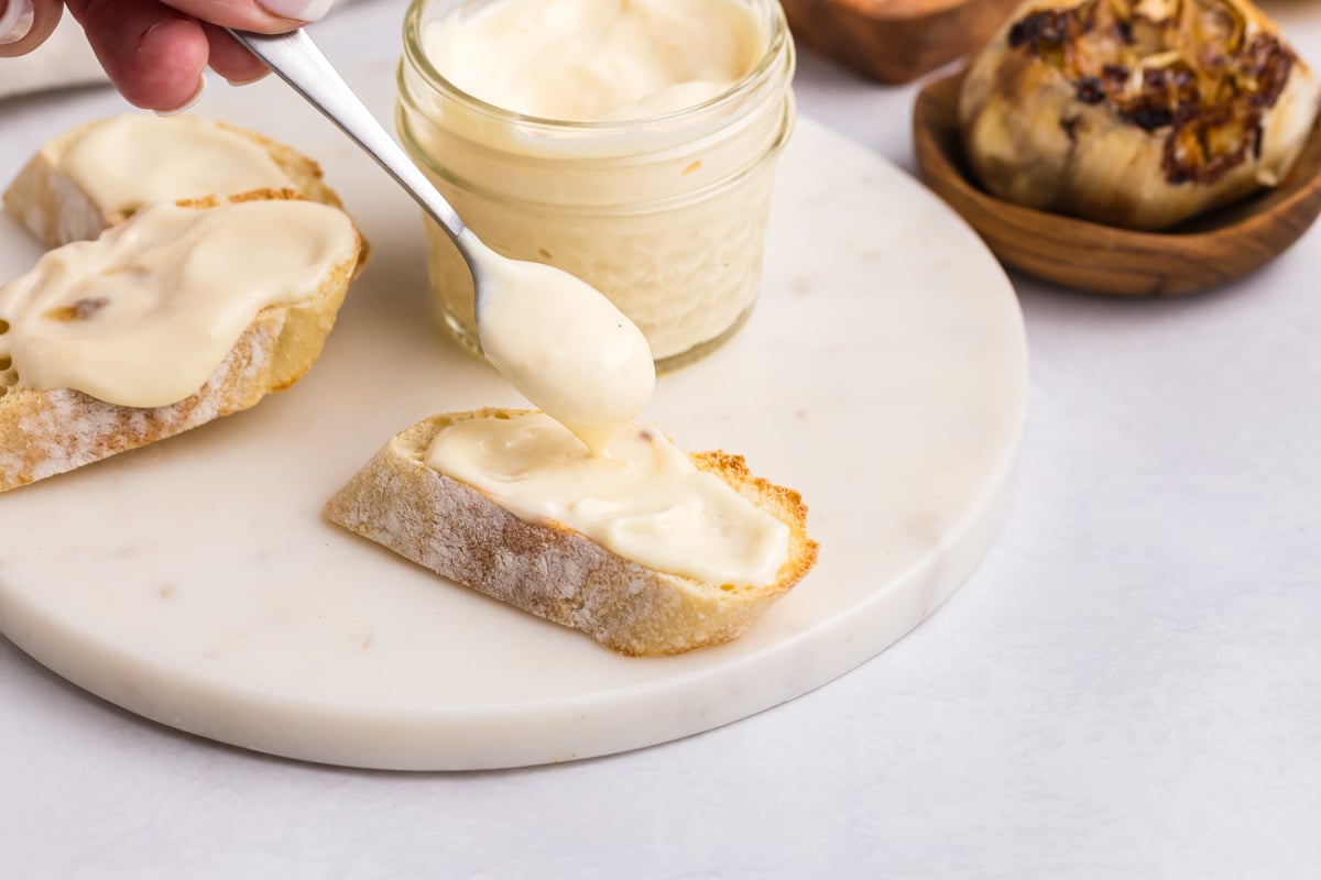 spoon adding mayonnaise to slice of bread