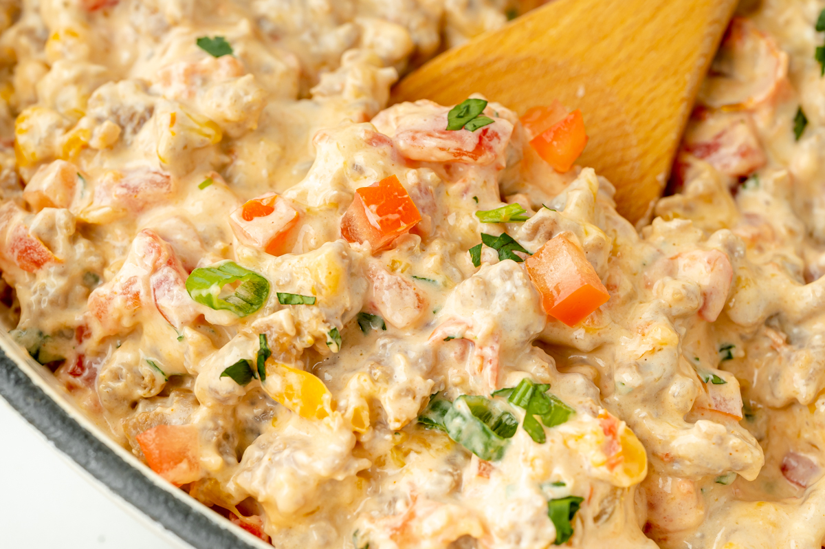 close up of wooden spoon in pan of sausage dip
