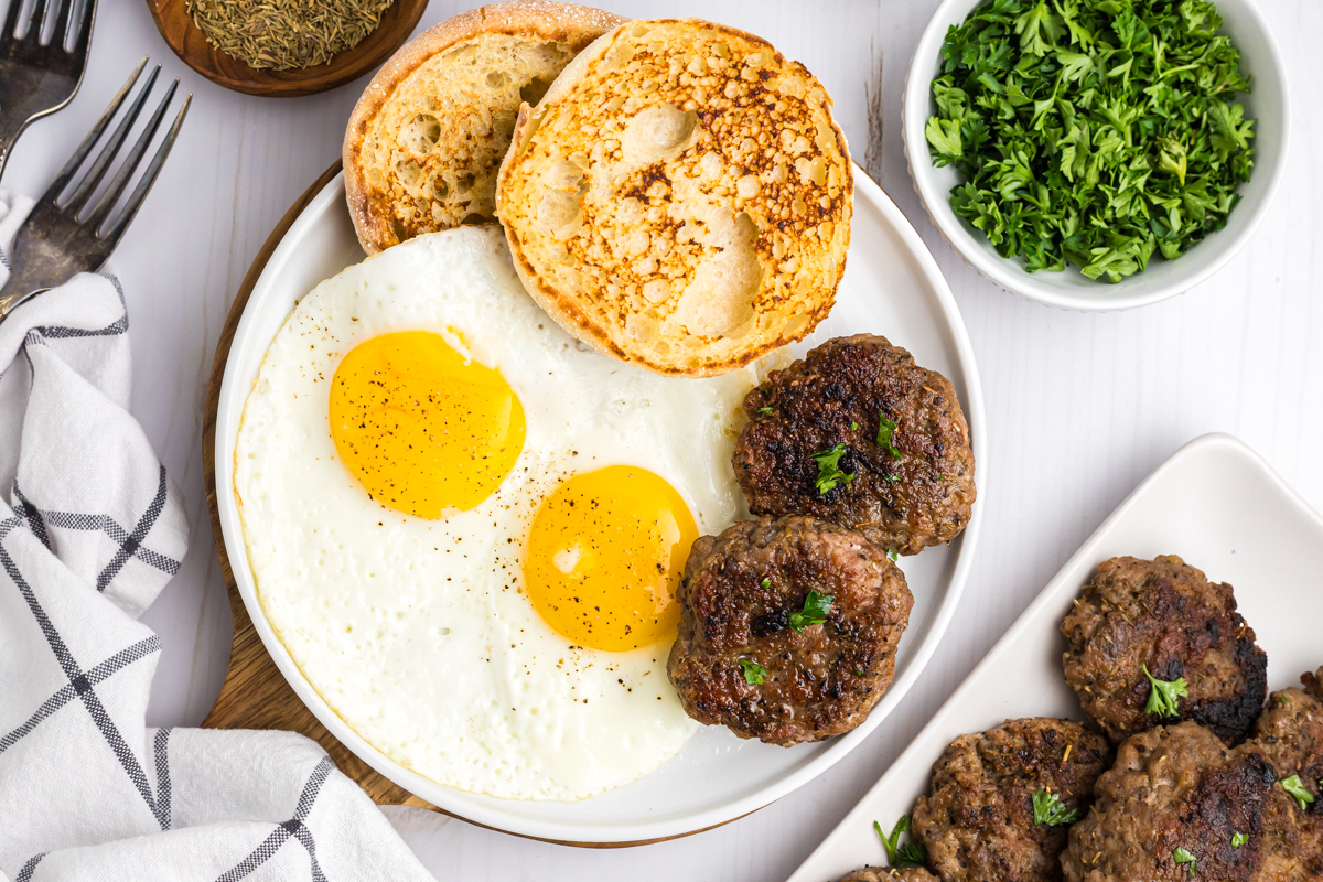 overhead shot of plate of eggs, toast and breakfast sausage patties