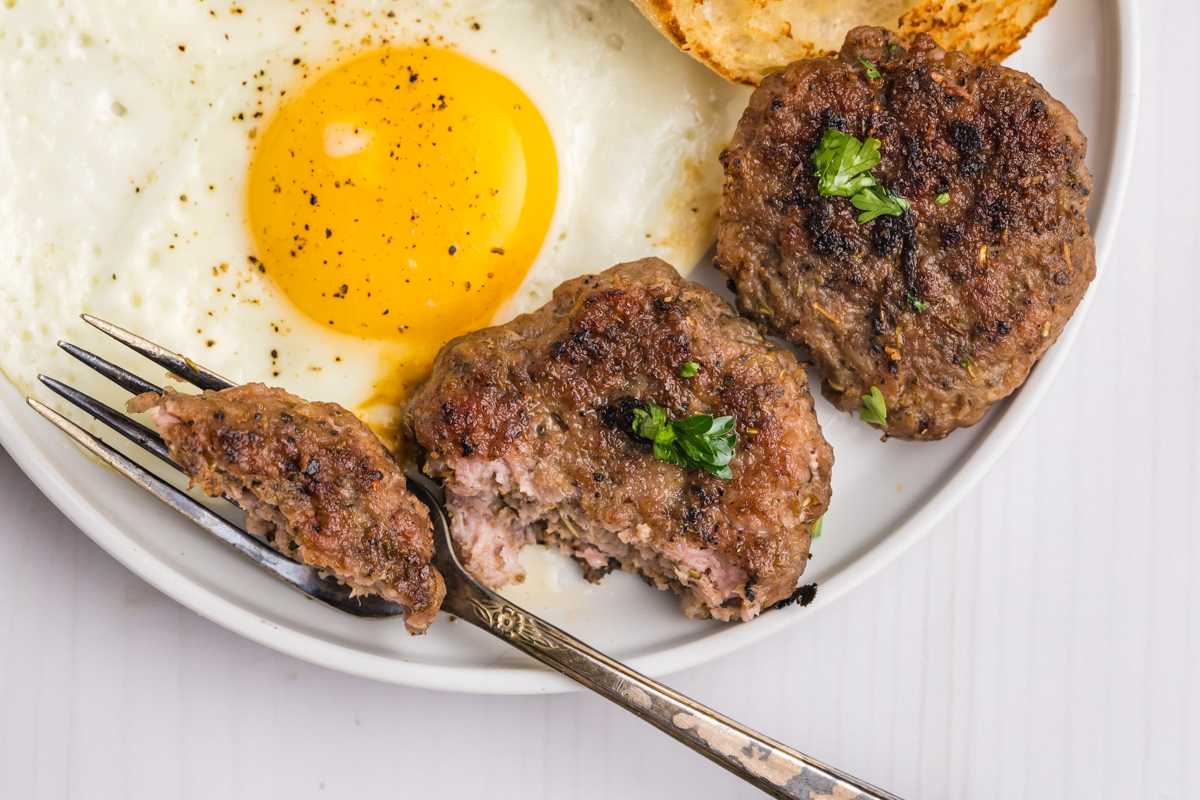 close up overhead shot of fork cutting breakfast sausage patty
