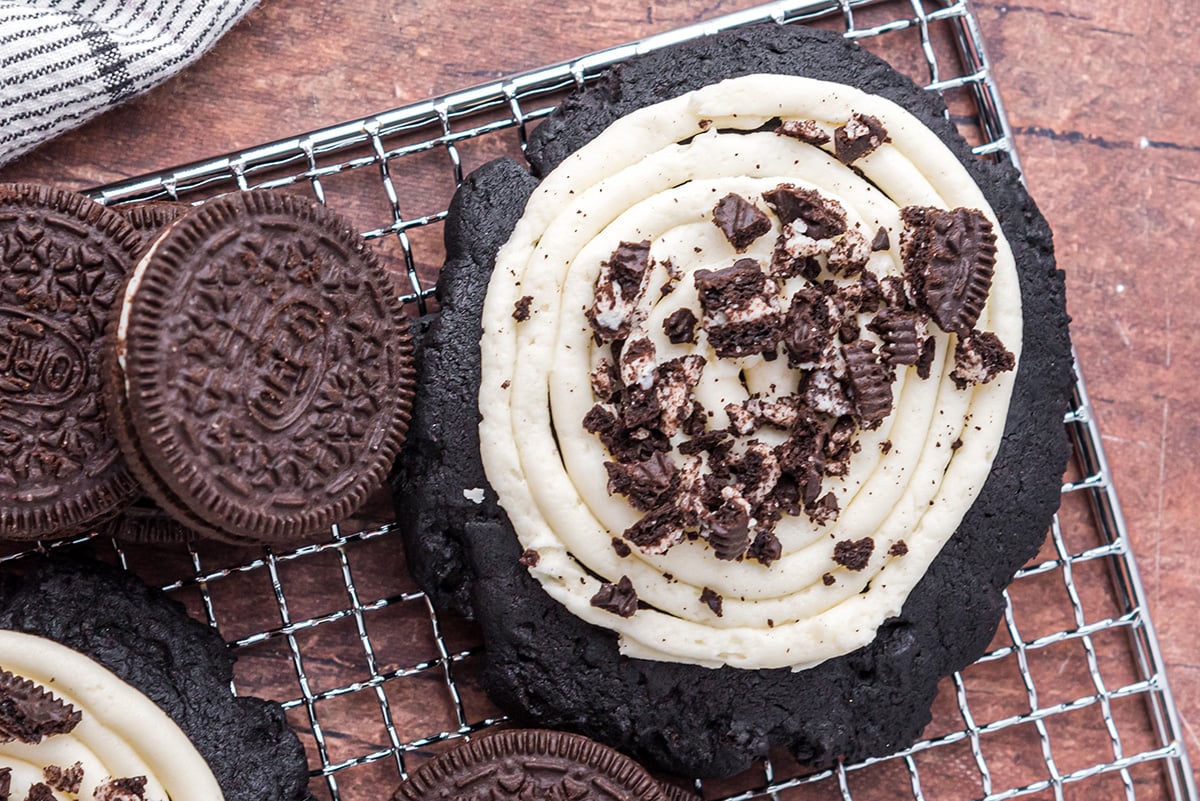 close up overhead shot of frosted cookie on cooling rack with oreos