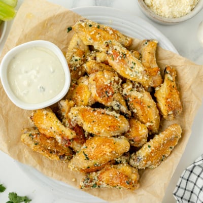 overhead shot of plate of garlic parmesan chicken wings with bowl of ranch