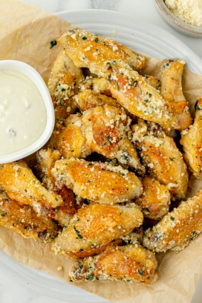 overhead shot of plate of garlic parmesan chicken wings with bowl of ranch