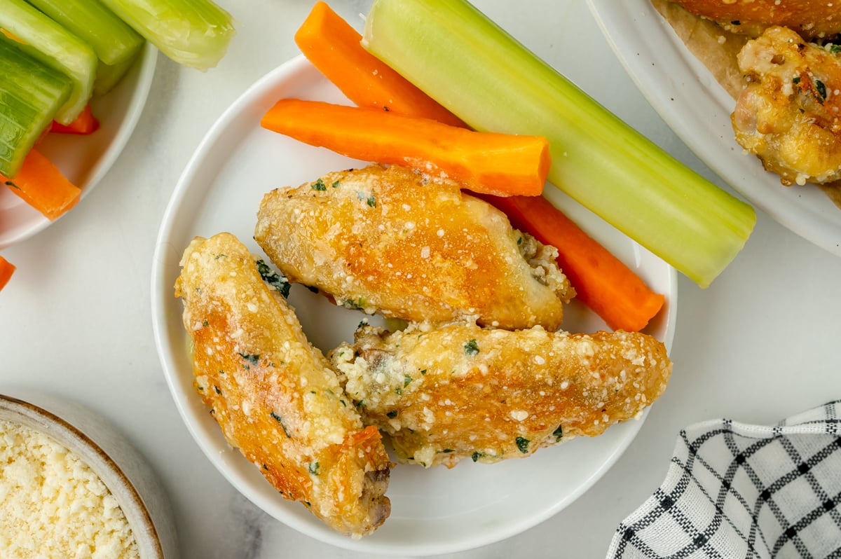 overhead plate of chicken wings with garlic parmesan sauce, carrots and celery